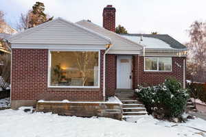 View of front facade with a chimney, entry steps, and brick siding