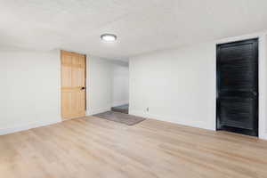 Empty room featuring light wood-style floors and a textured ceiling