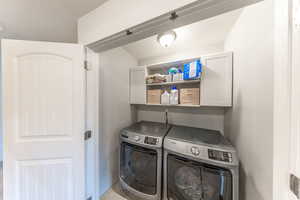 Laundry area featuring cabinet space, a textured ceiling, and washing machine and dryer