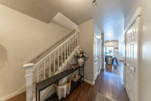 Stairs with wood finished floors and a textured ceiling