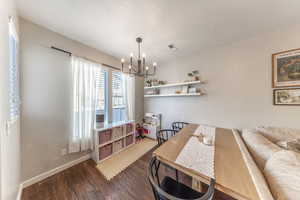 Dining space with dark wood-style flooring, hanging lights, and a textured ceiling