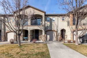 Mediterranean / spanish-style home with stucco siding, a balcony, stone siding, and a front yard