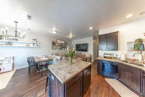 Kitchen featuring dark wood finish cabinetry, a center island, open shelves, a breakfast bar area, and a textured ceiling