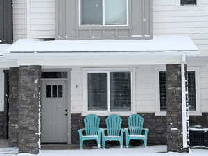 Snow covered property entrance featuring stone siding