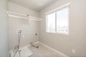 Laundry area featuring washer hookup, hookup for an electric dryer, and light tile patterned flooring