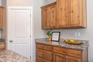 Kitchen featuring light stone countertops and wood finish cabinetry