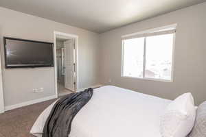 Carpeted bedroom featuring baseboards and ensuite bath
