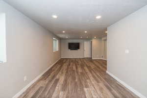Unfurnished living room featuring dark wood-type flooring and recessed lighting