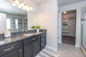 Full bath with a walk in closet, vanity, a stall shower, and light tile patterned floors