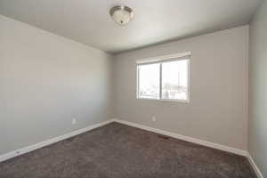 Spare room with baseboards and dark carpet