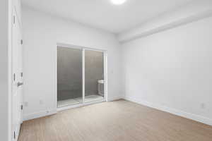 Bedroom opens to patio featuring light wood-type rnished bflooring and access to outside