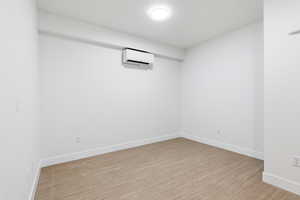 Living room with light wood-style flooring and a wall mounted mini split