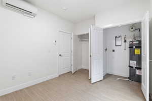 Bedroom with secured water heater, light wood-style flooring, and a closet
