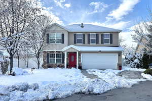 View of front facade featuring an attached garage and stone siding