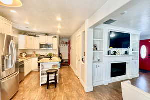 Kitchen with stainless steel appliances, a center island, a textured ceiling, a breakfast bar area, and built in shelves