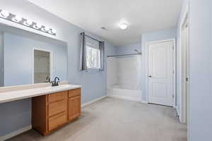 Primary ensuite Bathroom featuring vanity, shower / bathtub combination with curtain, and light carpet