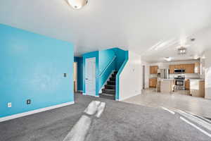Unfurnished living room with light colored carpet and light tile patterned floors