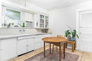 Kitchen featuring white cabinetry, a textured ceiling, glass fronted cabinets, light tile patterned floors, and light stone counters