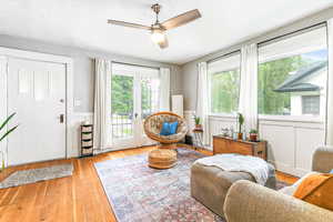 Sitting room with wainscoting, a ceiling fan, light wood-style floors, and a decorative wall
