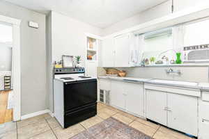 Kitchen with electric range, white cabinetry, a textured ceiling, and a textured wall