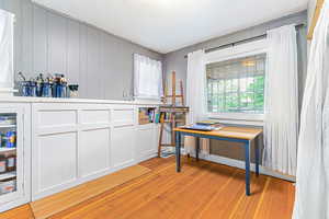 Office area featuring light wood-style floors, a textured ceiling, and wooden walls