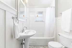 Full bath featuring toilet and shower / bath combination with curtain