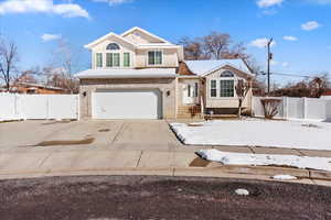 Traditional-style home featuring a gate, an attached garage, and driveway