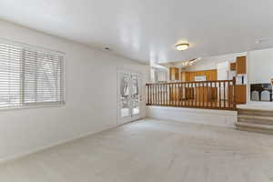 Empty room with light carpet and lofted ceiling