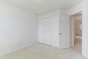 Unfurnished bedroom with light colored carpet and a closet
