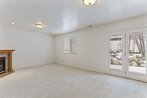 Unfurnished living room with a tiled fireplace and light colored carpet
