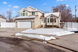 Traditional-style home featuring a gate, an attached garage, concrete driveway, and stucco siding