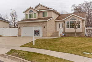 View of front of property featuring a gate, a garage, driveway, a shingled roof, and brick siding