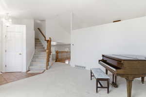 Living area featuring light colored carpet, lofted ceiling, hanging lights, and light tile patterned flooring