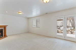 Unfurnished living room featuring a tile fireplace and light colored carpet