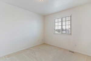 Spare room featuring light colored carpet and baseboards