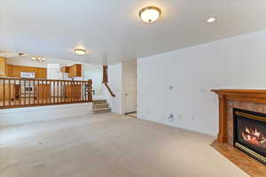Unfurnished living room with a tile fireplace and light colored carpet