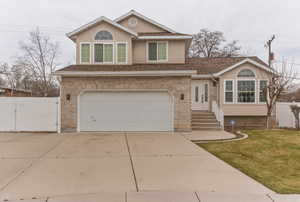 Traditional home with a gate, concrete driveway, an attached garage, and stucco siding