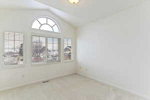 Unfurnished room with vaulted ceiling and light carpet