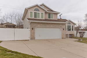 View of front of property featuring concrete driveway, a gate, a garage, stucco siding, and brick siding