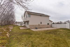 Rear view of house with a patio area, brick siding, and a fenced backyard