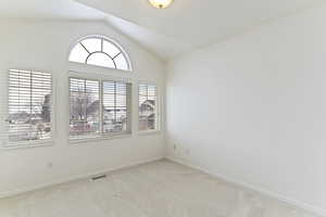 Empty room with light colored carpet and vaulted ceiling