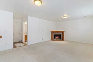 Unfurnished living room with light colored carpet and a tile fireplace