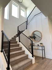 Stairway with wood-type flooring and a high ceiling