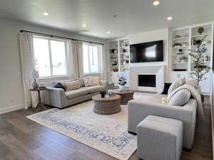 Living area featuring wood-type flooring, recessed lighting, a fireplace, and built in features