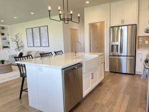 Kitchen with a kitchen bar, white cabinetry, stainless steel appliances, light stone countertops, and built in shelves
