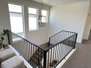 Stairs featuring carpet floors and a chandelier
