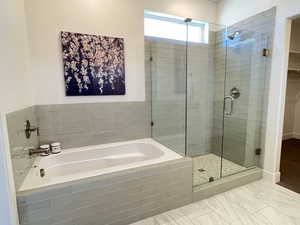 Full bathroom featuring a garden tub, a shower stall, and a spacious closet