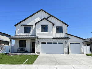 Modern farmhouse featuring a standing seam roof, covered porch, board and batten siding, and driveway