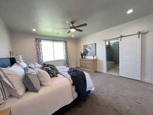 Bedroom with a barn door, carpet, a ceiling fan, connected bathroom, and recessed lighting