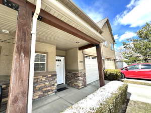 Entrance to property featuring stone siding, stucco siding, and a porch